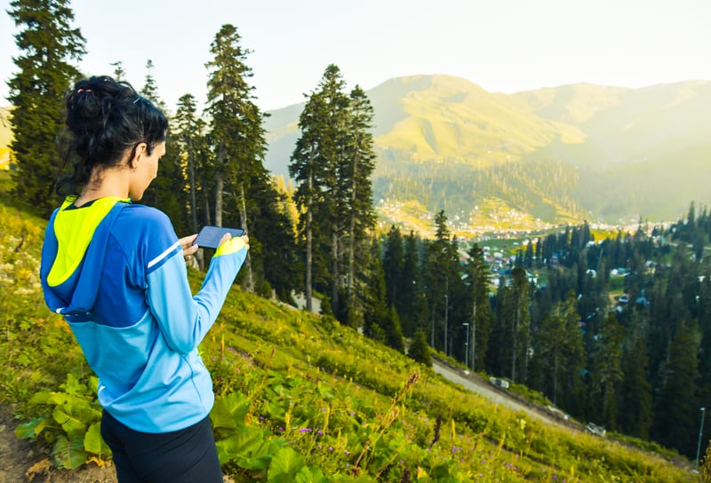 Person holding smartphone in scenic mountain location