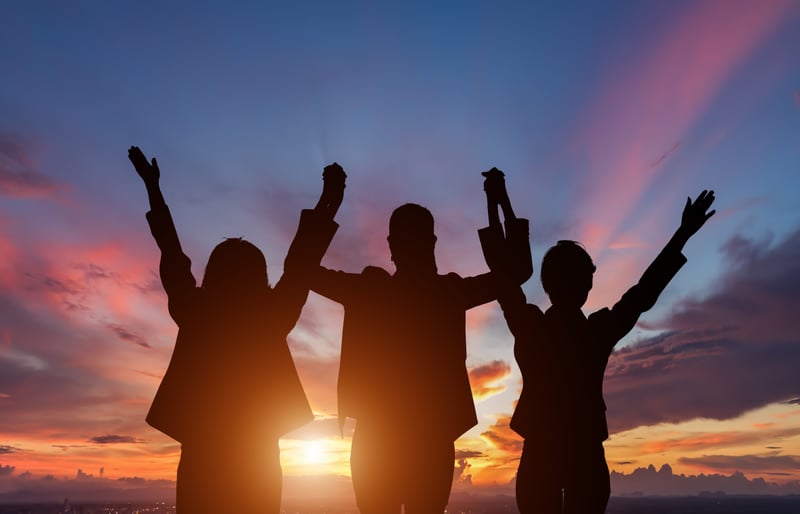 Three people silhouetted against beautiful sunset
